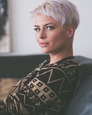Image shows short-haired person looking sideways at the viewer.