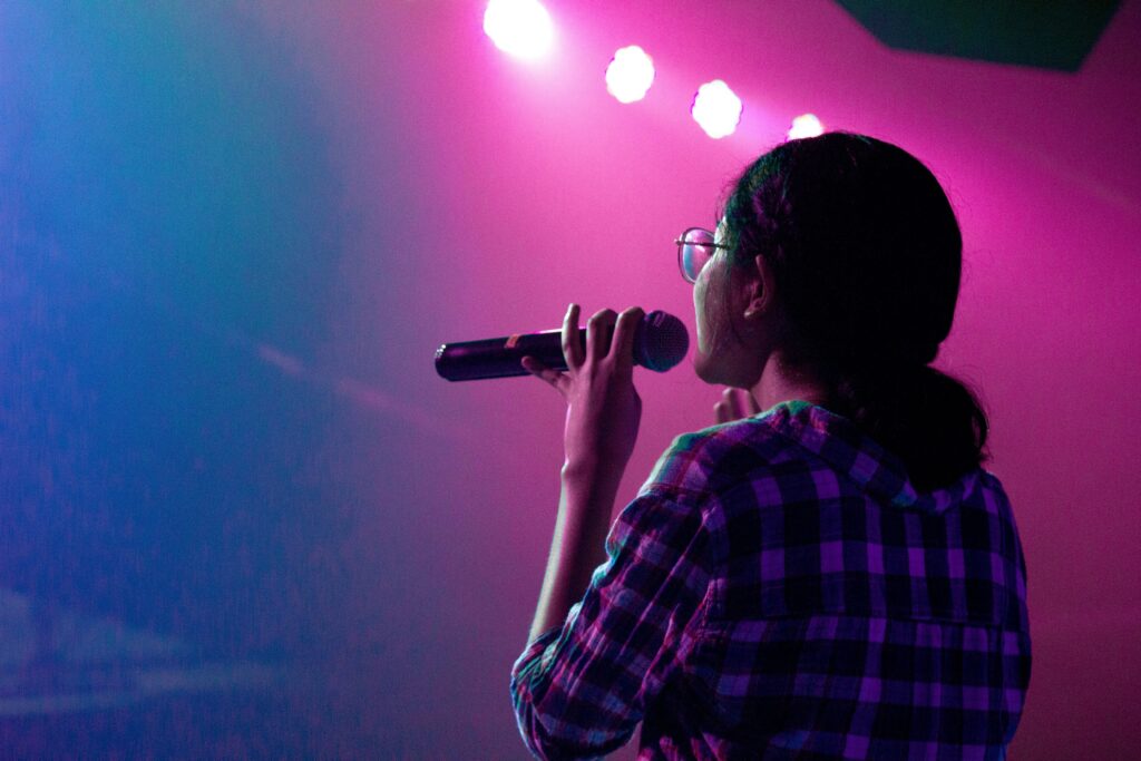 Helping Clients Reclaim Their Voice. Image shows person holding microphone to their mouth while facing away from the viewer.