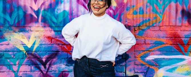 A woman with resilience stands in front of a colorful wall.