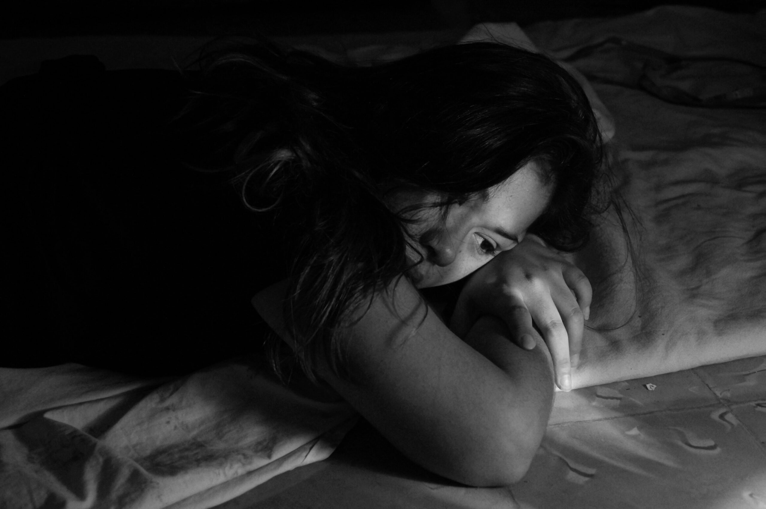 Woman laying in bed, looking pensive, perhaps experiencing body grief