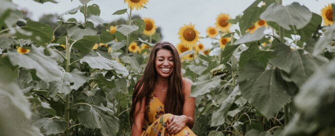 A woman sits in a field of flowers as a form of self-care.
