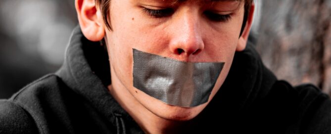 A man with tape over his mouth is silent about IPV