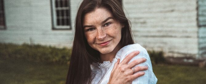 Skin Hunger: Image shows woman hugging self and smiling while looking at camera