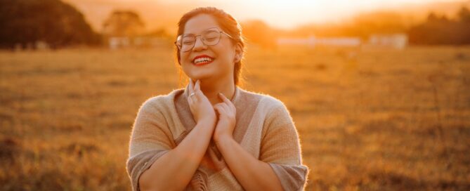 woman smiling in a field practicing gratitude for better sex