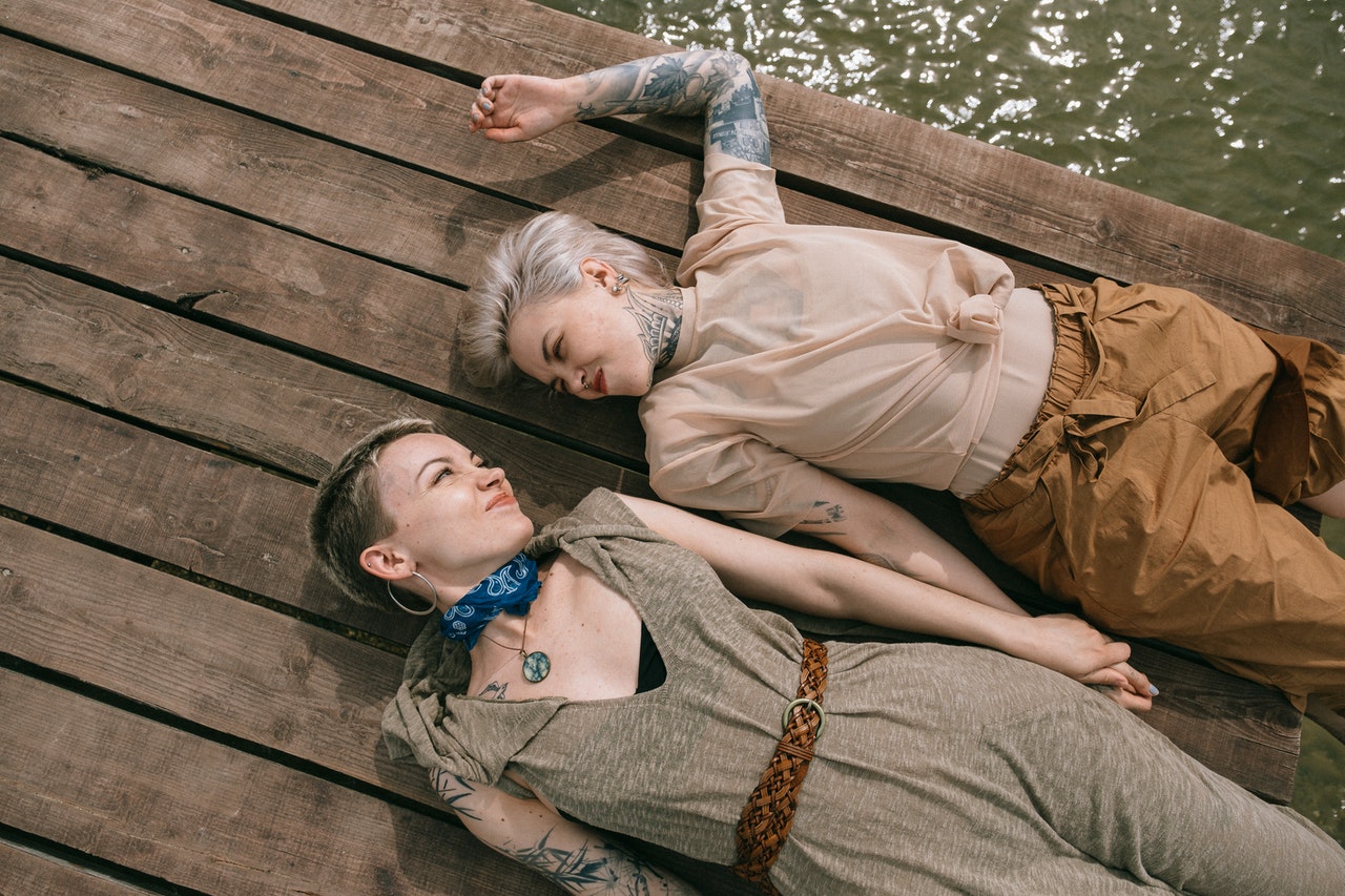 a romantic couple of capricorns lays together on a dock looking into each other's eyes