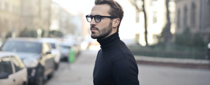 a man in glasses walking across the street because he learned to manage practitioner burnout