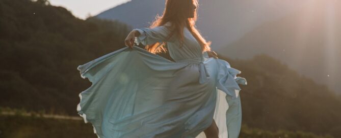 a woman in a dress dancing in a field because she learned tools and rituals for sexual wellness