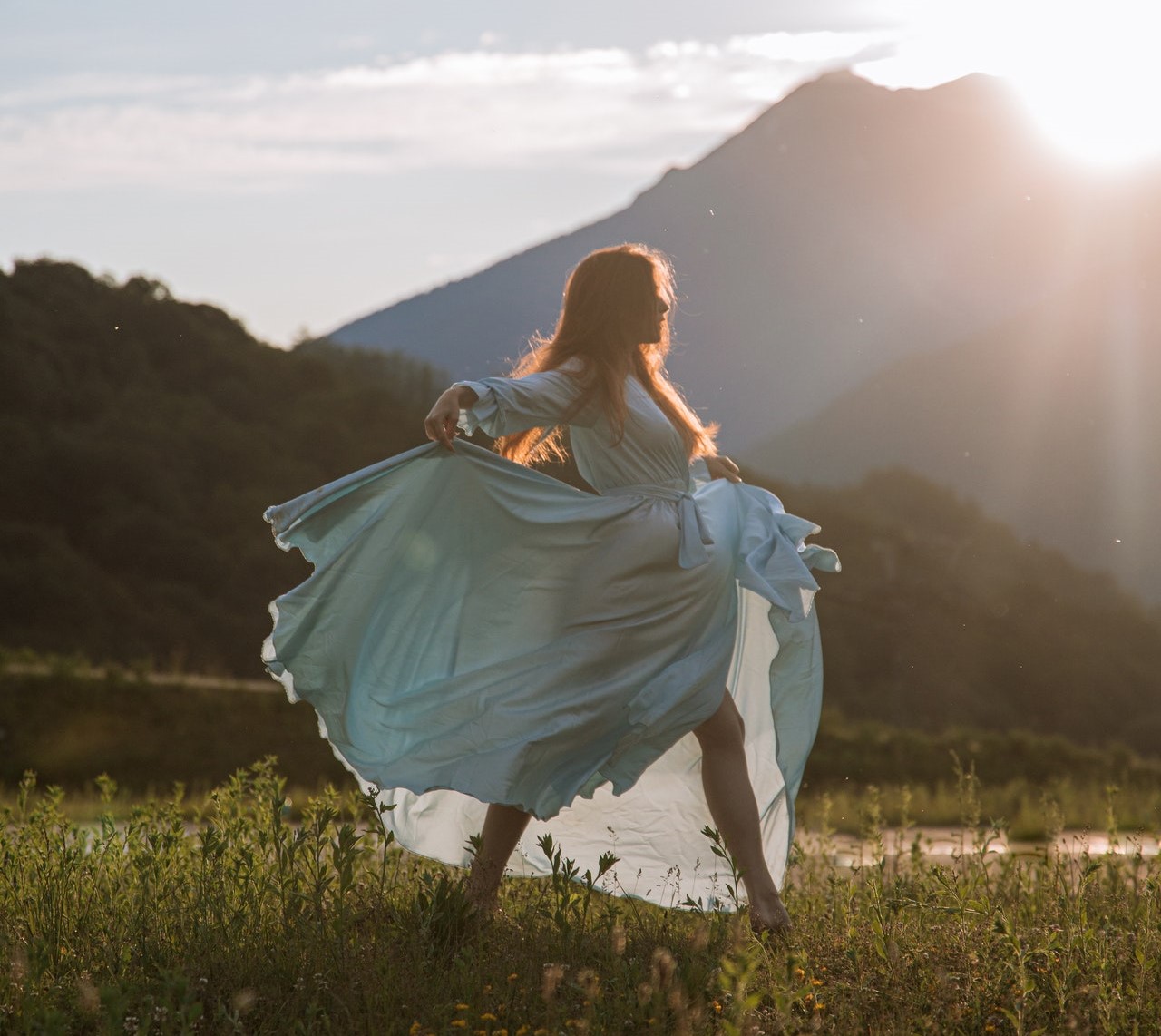 a woman in a dress dancing in a field because she learned tools and rituals for sexual wellness