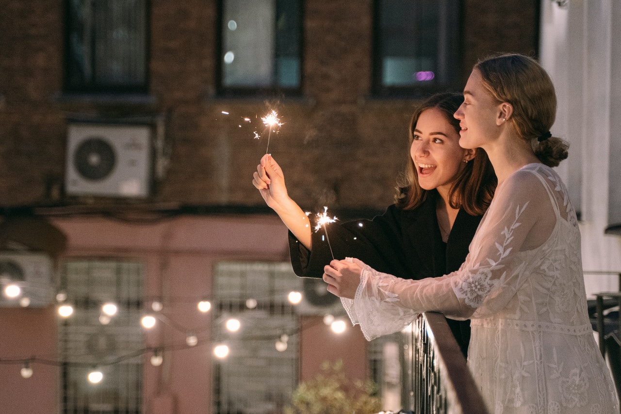 two women with sparklers on a balcony representing gemini and aries