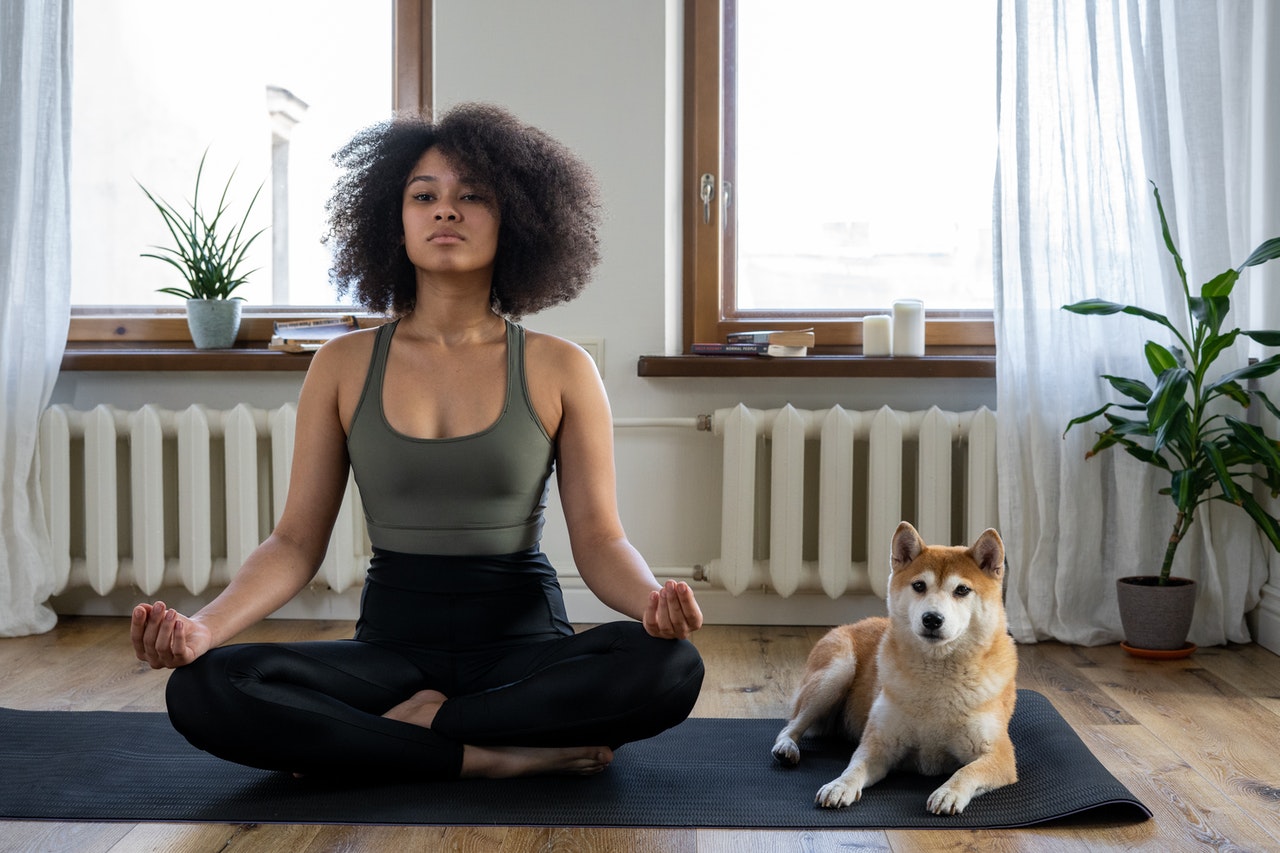 a woman sitting cross legged on a yoga mat with a dog practicing mindfulness for her sex coaching practice
