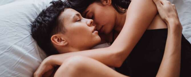 Two women embracing in bed. Women loving women can overcome lesbian bed death.