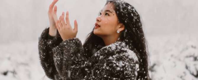 A woman celebrating the Winter Solstice with snow falling around her.