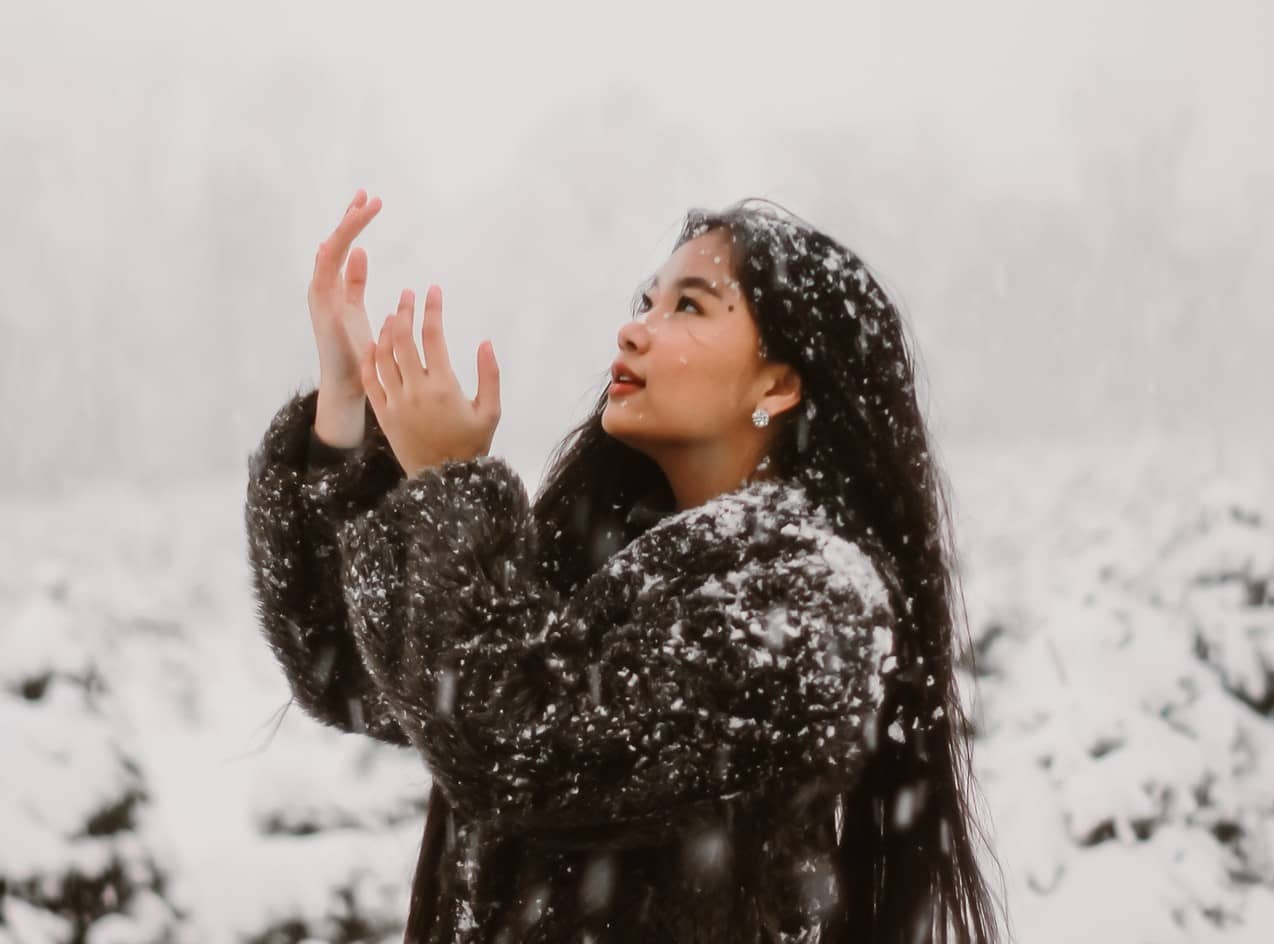 A woman celebrating the Winter Solstice with snow falling around her.