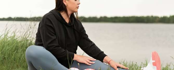 A woman in the grass preparing for naked yoga.