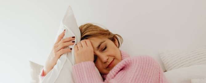 woman in a pink top hugs a pillow after experiencing orgasm as little death