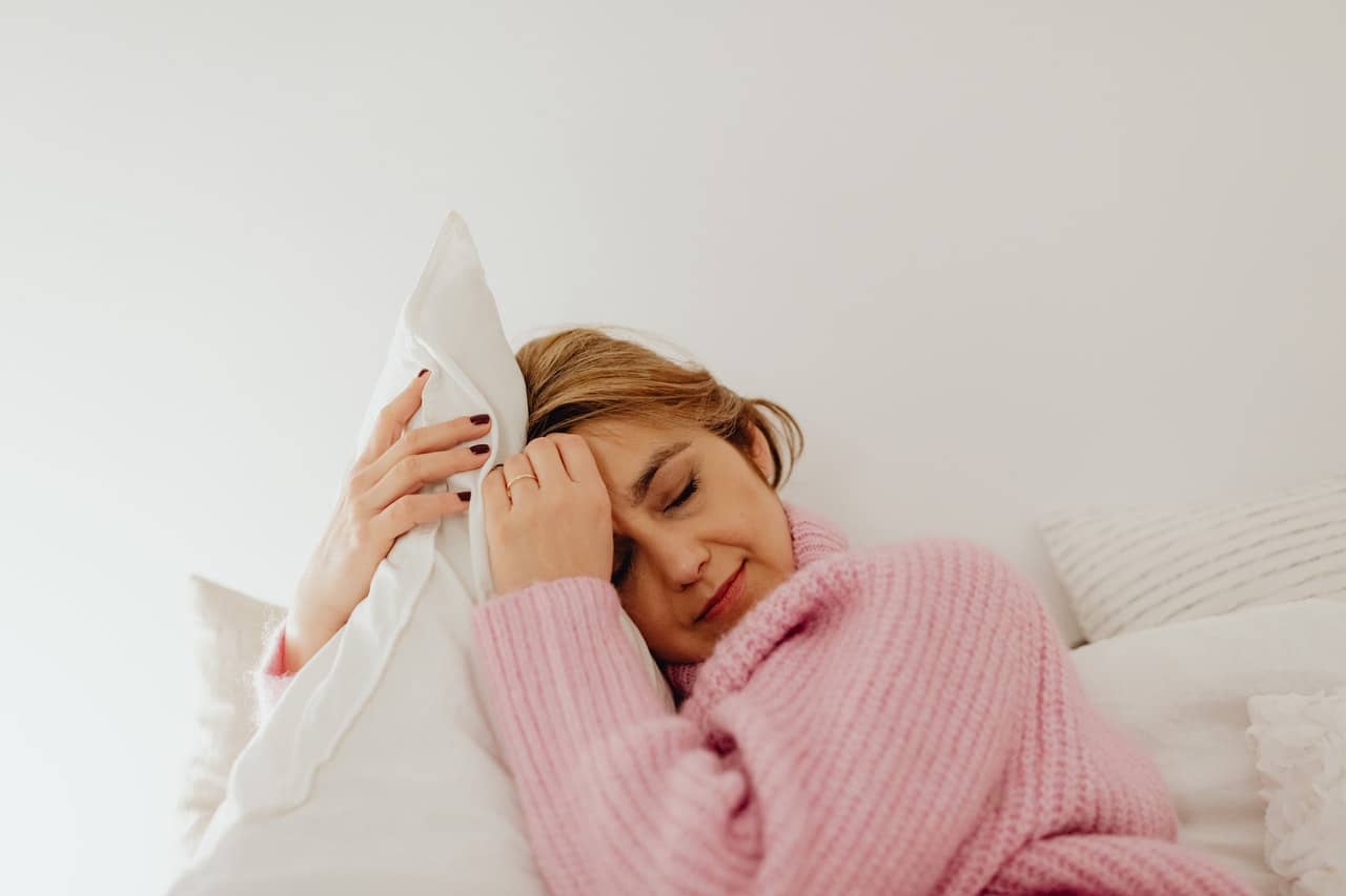 woman in a pink top hugs a pillow after experiencing orgasm as little death