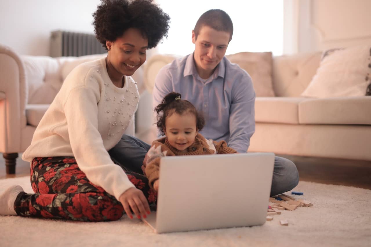 two parents happily sitting with their child looking at a screen