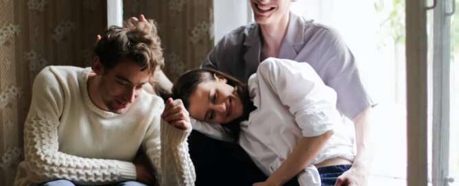 three lovers smiling and laughing together after being coached about ethical non-monogamy