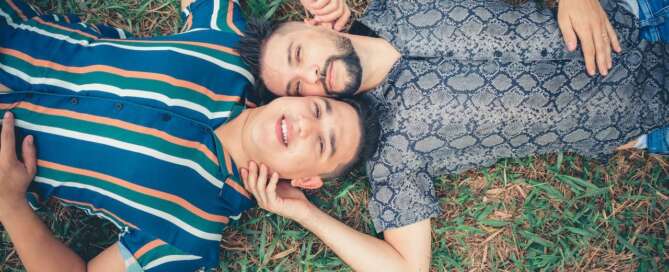 Two men lay on the ground touching each other and smiling after coaching addressed their opposite desire styles.