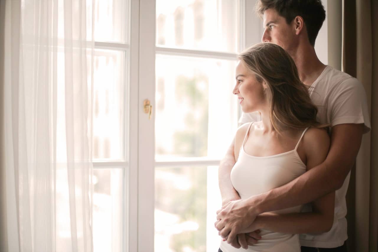 a couple embraces while looking out the window experiencing more intimacy after realizing why people seek sex coaching