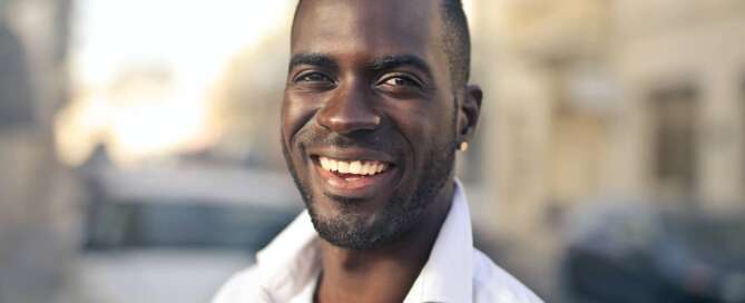 a man in a white collared shirt smiles at the camera confidently, because he overcame his fears about a career change to sex coaching