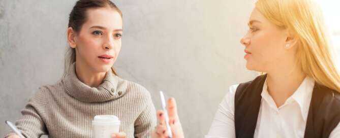 two women sit together writing in their planners while discussing the different careers in sexuality that are available