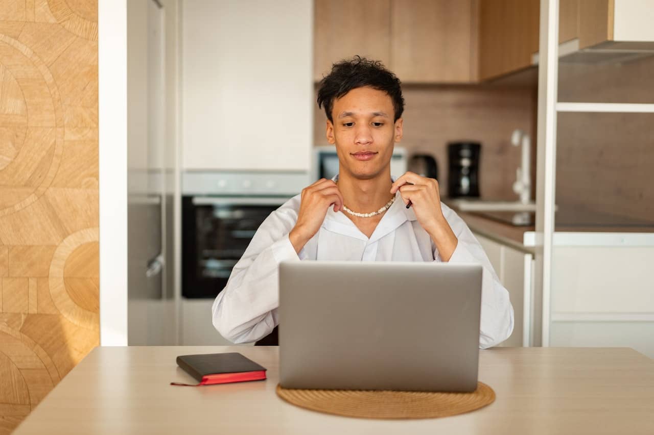 a person in a white shirt sitting at a table with a book and a laptop in front of them, figuring out how to know if they are ready for a career change.