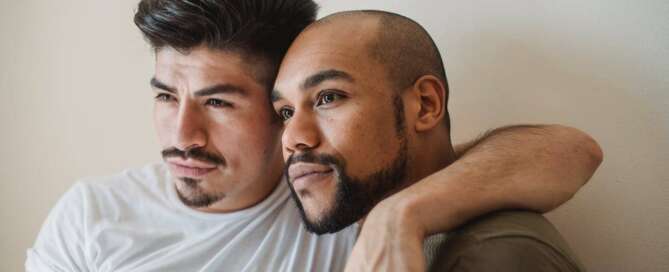 two male presenting people embrace and look off center from the camera after experiencing sex coaching for asexual and aromantic clients