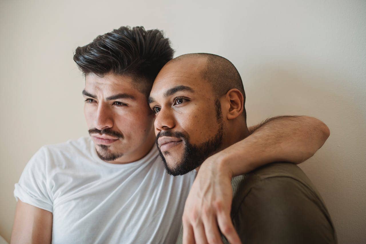 two male presenting people embrace and look off center from the camera after experiencing sex coaching for asexual and aromantic clients